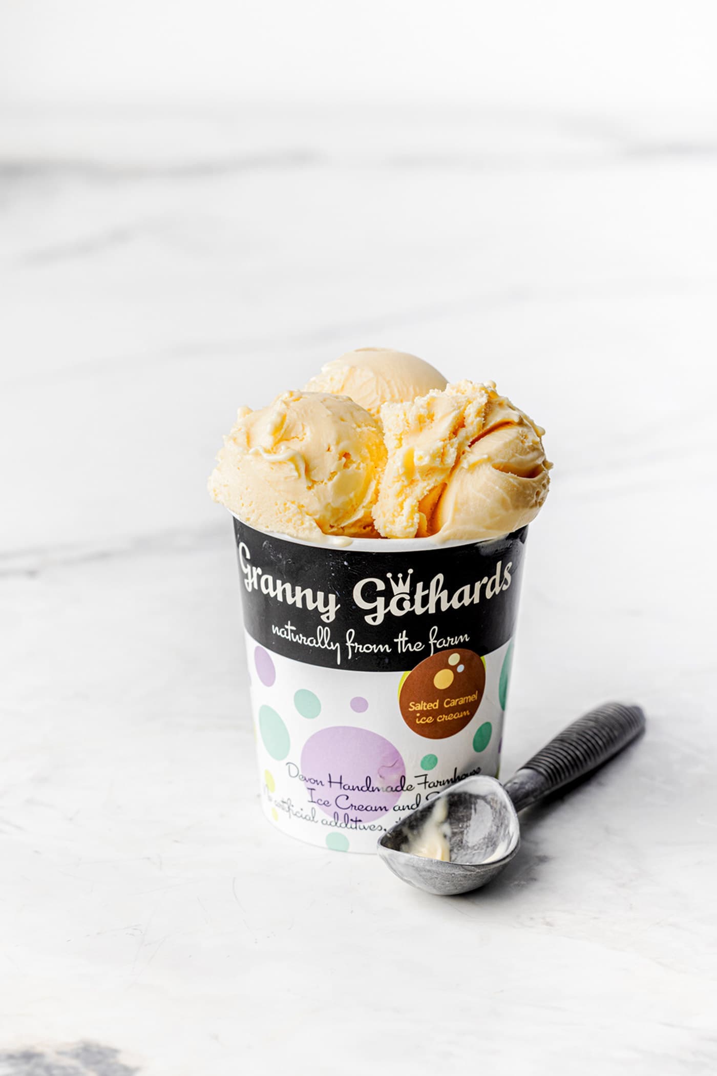 A Granny Gothards pot filled with vanilla ice cream, with a scoop beside it