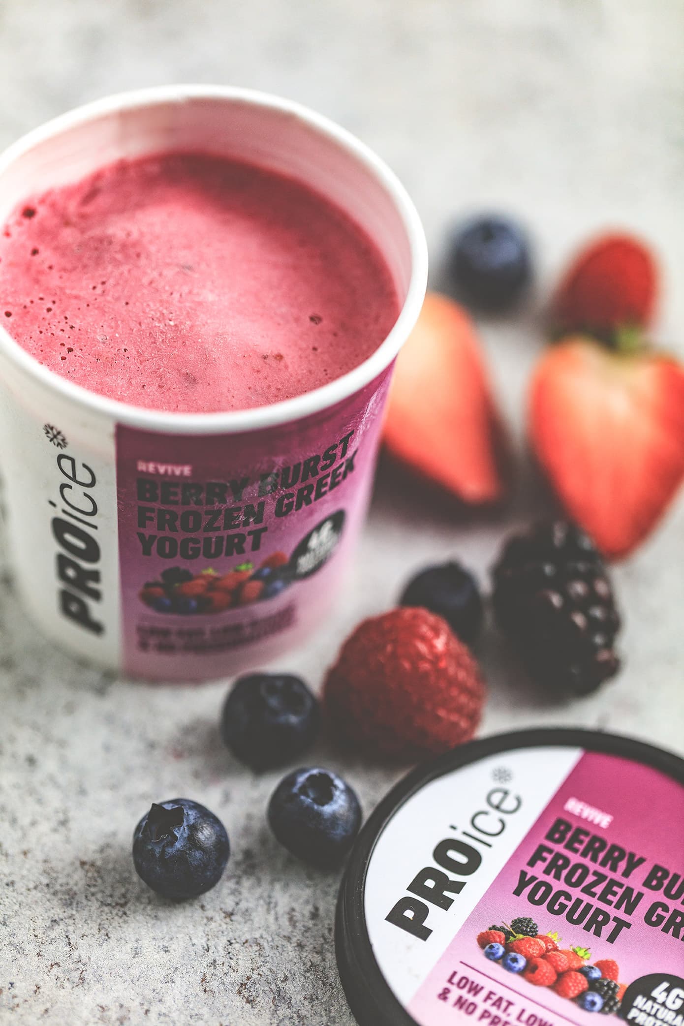 Close-up of an open tub of PROice Berry Burst Frozen Greek Yogurt with mixed berries