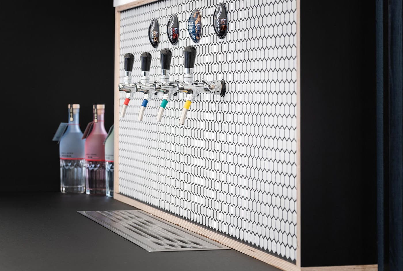 A tap wall with hexagon tiles and Chapel Down gin bottles at a Curious Brewing bar