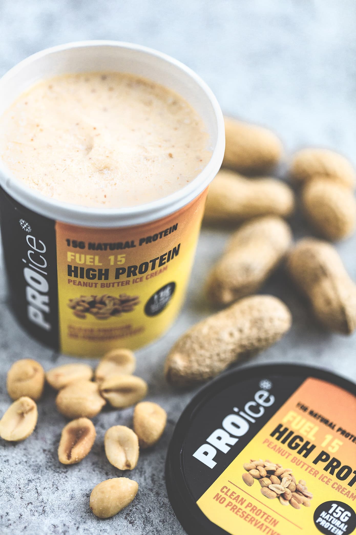 An open tub of PROice Fuel 15 High Protein ice cream with peanuts