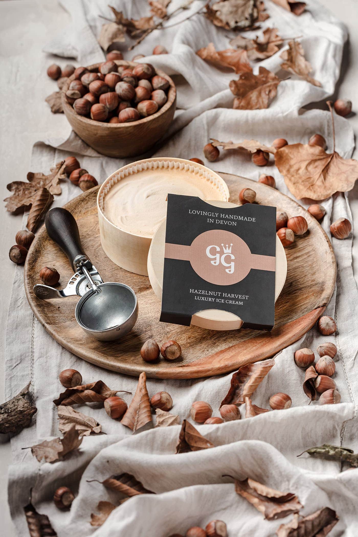 A Granny Gothards ice cream tub styled with hazelnuts, a scoop and autumn leaves