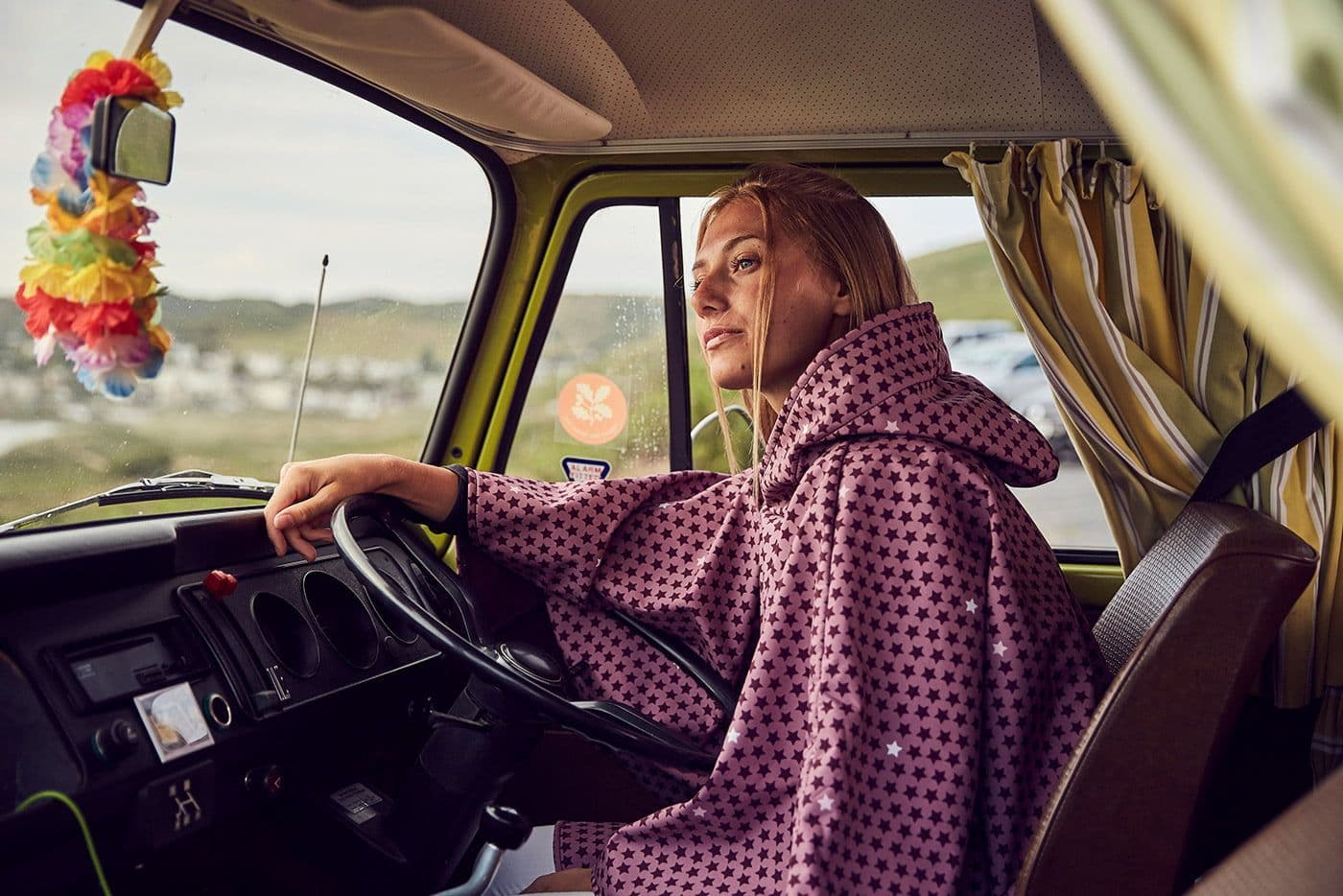 A woman in a star print Ponchella poncho driving a vintage campervan