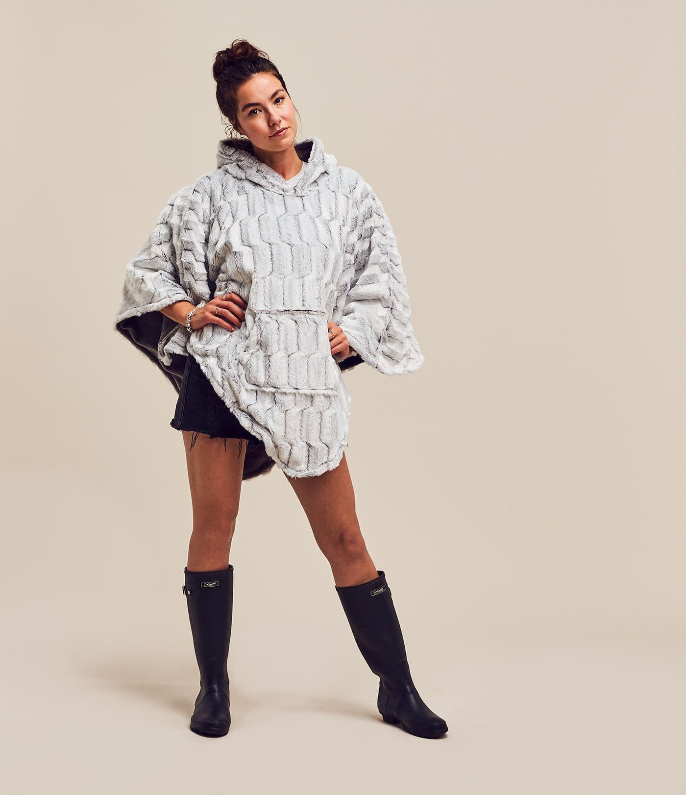 A woman in a grey patterned Ponchella poncho and black wellies