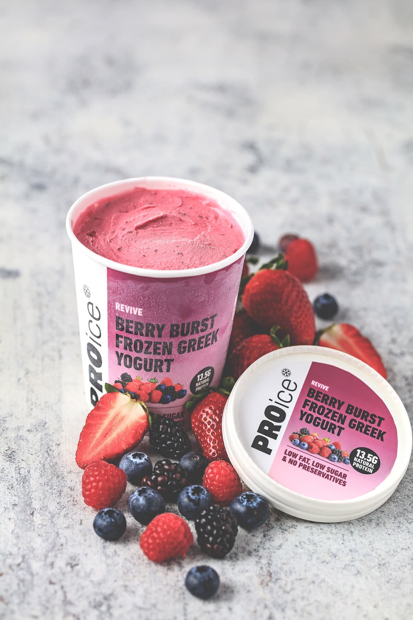 An open tub of PROice Berry Burst Frozen Greek Yogurt with strawberries, raspberries and blueberries